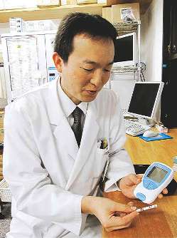 簡易迅速測定機を手にする倉田寛行さん＝岐阜県土岐市のささゆり薬局土岐店で