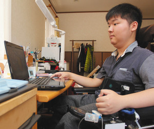 勤務先から貸与されたパソコンで画像を加工する河本圭亮さん＝名古屋市内の自宅で