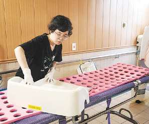 機械浴のストレッチャーを掃除する林祐実さん＝岐阜市の山内ホスピタル介護老人保健施設で