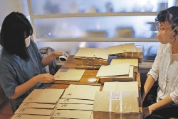 支援員に見守られながら作業する女性利用者（左）＝昭和区の「おうち菓子　マダムアン」で