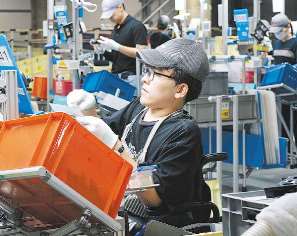 高さが調節できる作業台で内装部品の組み付け作業をする荒井さん＝愛知県稲沢市の池戸製作所で