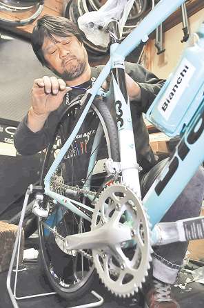 てきぱきとスポーツ自転車の整備をする石河店長＝豊橋市鍛冶町のホットギアで