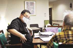 勤務先の有料老人ホームで利用者と雑談する岩渕成穂さん（左）＝神奈川県藤沢市で