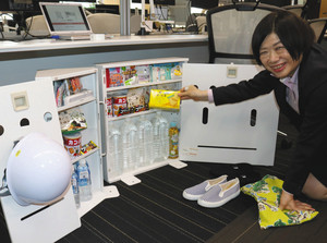 水やお菓子など、机下の備蓄品を紹介する大島さん＝東京都中央区の内田洋行で