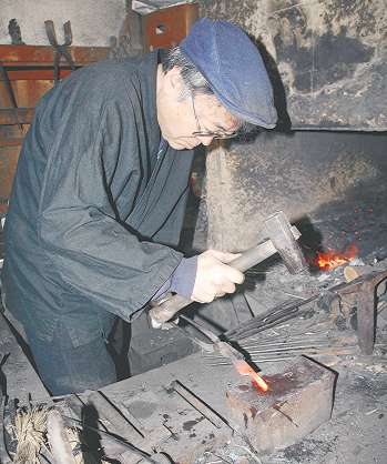 １０００度近い鋼をハンマーで打つ広瀬さん＝豊田市足助町で