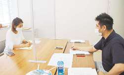 中央に置いたスマートフォンのスピーカー機能で相談内容を聞き取る社会保険労務士（左）とスペイン語の通訳＝津市羽所町のアスト津で