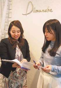 ディマンシェスタイルを手に社員と話す三輪さん(左）＝岐阜市寺田のディマンシェで