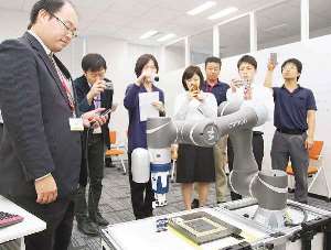 人と一緒に働く協調ロボットをＰＲするオムロンの担当者（左）＝名古屋市で