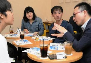メーカーの仕事内容を学生に説明する小川保典さん（右）＝名古屋市昭和区の「知るカフェ名古屋大学前店」で