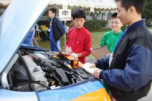 高校生に教わりながら車を点検する子どもたち＝中川区の中川商業高で