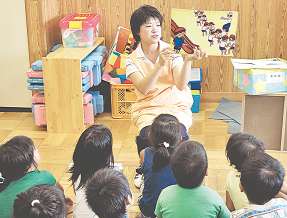 園児らに紙芝居を見せる梅徳さとみさん＝豊橋市松葉町のくるみ保育園で