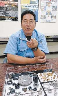 自社製品を前に転職後の仕事や生活について語る倉本昌幸さん＝長野県駒ケ根市のナパックで