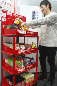 オフィスグリコの棚からお菓子を選ぶ社員＝東京都内のサイゲームスで