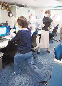 「ＳＴＯＰ座りすぎ」の時間に立って運動する豊田安全衛生マネジメントの社員＝愛知県豊田市で