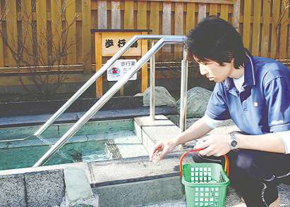 塩素濃度を調べるため湯を採取する辻克比古さん＝東栄町のとうえい温泉で