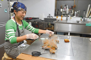 「おへそキッチン」でパウンドケーキを袋詰めする新庄まきさん＝東京都国立市で