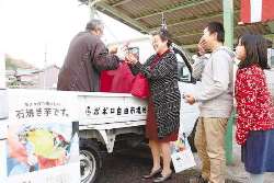 ポポロの支援を受ける男性（左）から焼き芋を受け取る客＝岐阜市八代で