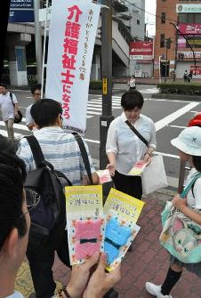 介護福祉士を紹介する冊子などを配布する専門学校の教員＝四日市市の近鉄四日市駅前で