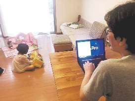 保育所が休みとなり、自宅で子どもを遊ばせながら仕事をするエイチームの男性社員＝同社提供